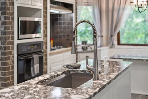 Contemporary kitchen with marbled island countertop and stainless steel appliances.