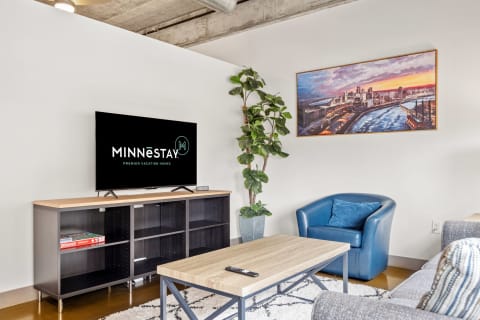Contemporary living room with a flat-screen TV, artwork, and blue armchair.