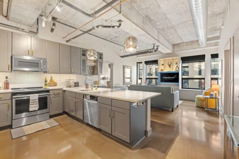 Modern kitchen with gray cabinetry and stainless steel appliances.