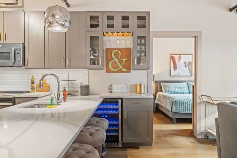 Stylish kitchen with gray cabinets and a view of a cozy bedroom.