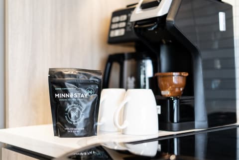 A modern kitchen scene with a coffee maker, white mugs, and a bag of MINNESTAY coffee.