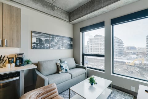 Modern living room with gray sofa, large windows, and a view of a construction site.