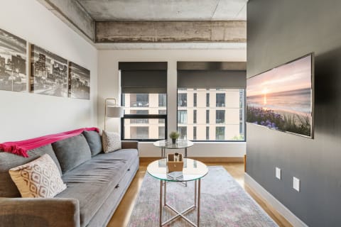 A contemporary living room with a gray sofa, decorative pillows, and large windows.