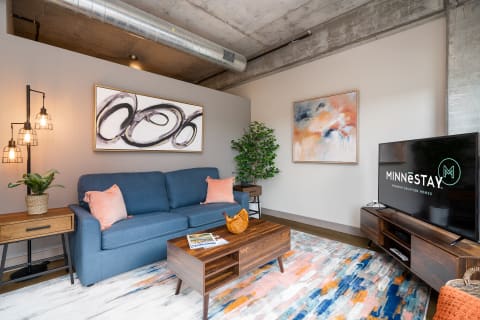 A cozy living room showcasing a blue sofa, abstract art, and decorative elements.