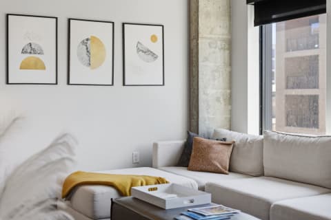 Stylish living room with light-colored sofa, decorative cushions, and modern art on the walls.