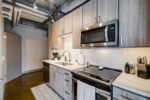 A modern kitchen featuring wooden cabinets, a stainless steel microwave, and a polished countertop.