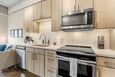 A contemporary kitchen with wooden cabinets, a stainless steel microwave, and a sleek countertop.