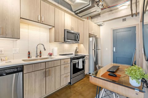 Contemporary kitchen with a workstation featuring wooden cabinets, stainless steel appliances, and a small desk.