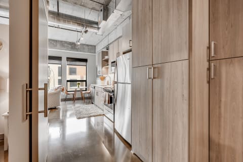 Modern kitchen with wooden cabinets and stainless steel appliances, featuring a dining area.
