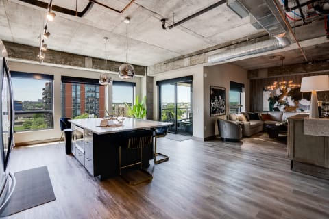 Open-concept apartment with kitchen island, large windows, and cozy living room.