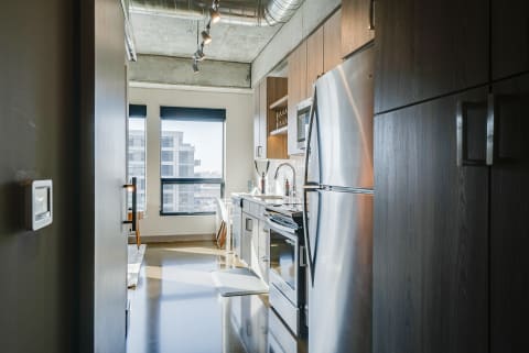 Modern kitchen with stainless steel appliances and natural light from a window overlooking an urban setting.