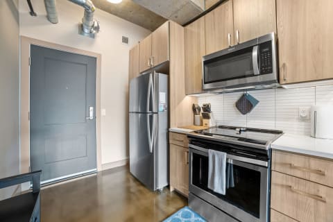 Contemporary kitchen with stainless steel fridge, oven, and wooden cabinets.