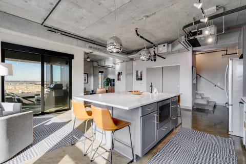 A contemporary kitchen featuring a large island, stylish bar stools, and a glass door leading to a balcony.