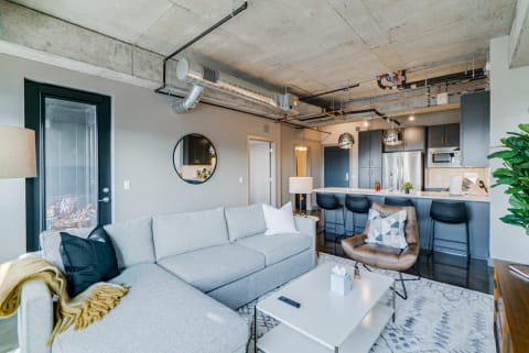 Modern living room with sectional sofa, coffee table, and stylish kitchen in the background.