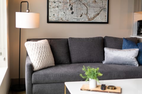 Modern living room corner with a gray sofa, decorative pillows, and a floor lamp.