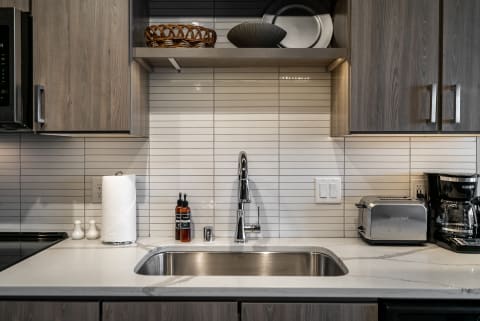 Sleek modern kitchen with stainless steel sink, gray cabinetry, and marble countertop.