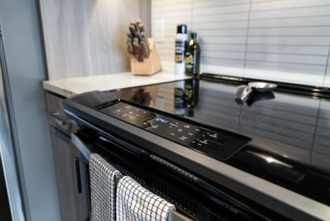 Modern kitchen with a black stove, knife block, and cooking supplies.