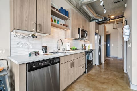 A modern kitchen featuring light wood cabinets, stainless steel appliances, and colorful glass decorations.