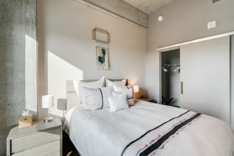 A contemporary bedroom with a bed, decorative pillows, and a woven wall hanging.