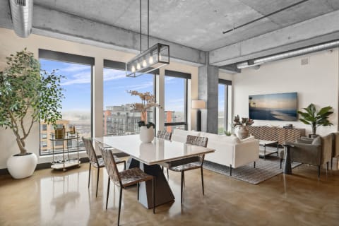 A stylish modern apartment featuring a dining table, indoor plants, and living area with a television.