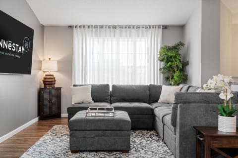 Inviting living room featuring a gray sectional sofa, light curtains, and modern decor.