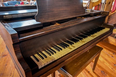 A vintage wooden piano with worn ivory and black keys, reflecting a cozy interior ambiance.