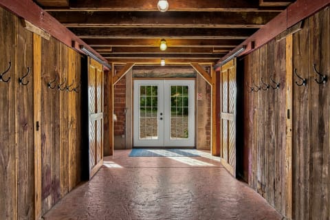 A rustic barn-style entryway with wooden walls and beams, featuring French doors leading outside.