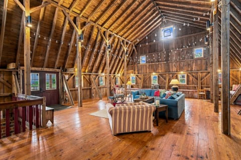 Spacious living room featuring wooden beams and bright light, with comfortable sofas and rustic decor.