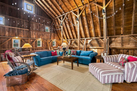 Rustic barn-style living room with wooden walls, colorful sofas, and cozy lighting.