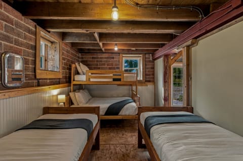 A rustic bedroom featuring wooden bunk beds and exposed brick walls, designed for comfort and charm.