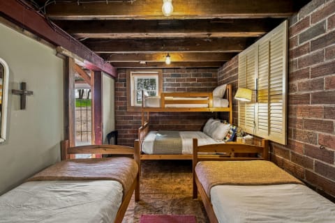Interior view of a rustic bunk room with exposed brick walls and wooden bunks.
