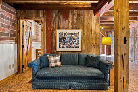 A deep blue polka-dot sofa in a rustic room with reclaimed wood walls and colorful artwork.
