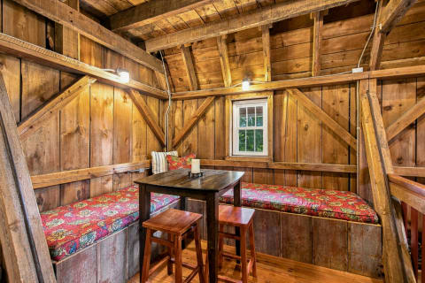 A warm, rustic hideaway with wooden walls, cushioned benches, and a small table.