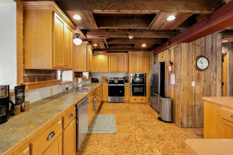 A rustic kitchen with wood cabinetry, stainless steel appliances, and exposed beam ceilings, creating a cozy and functional space.