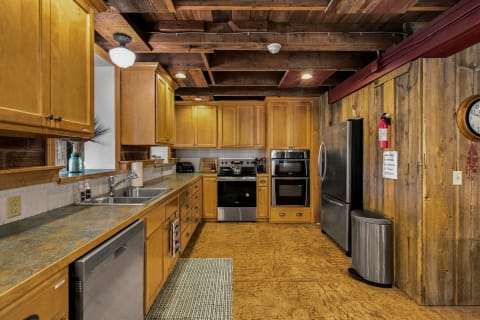 A rustic kitchen with wooden beams, honey-toned cabinetry, stainless steel appliances, and a cozy atmosphere.