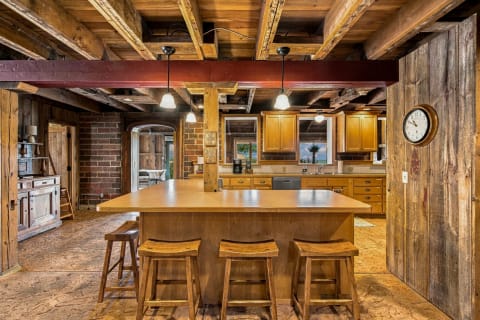 A cozy kitchen with a wooden island, exposed beams, and brick accents, perfect for cooking and conversation.
