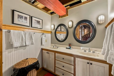 Rustic bathroom with double-sink vanity, white towels, and wooden beams.