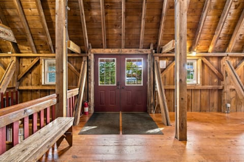 A beautifully crafted wooden entryway with beams, planks, and red double doors.