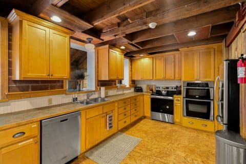 Rustic chic kitchen with wood cabinetry, modern appliances, and exposed beams.