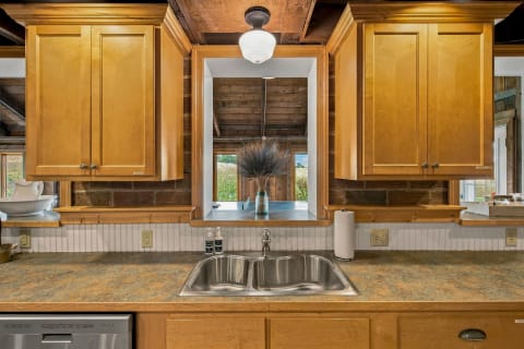 View of a rustic kitchen with wooden cabinetry, a stainless steel sink, and decorative elements, offering a warm and welcoming atmosphere.