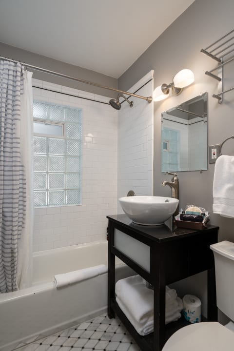 A stylish bathroom featuring a bathtub, vessel sink, and modern decor.
