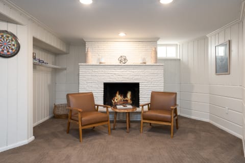 Interior of a cozy living room featuring a fireplace, two chairs, and decorative elements.