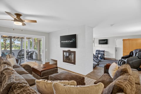 Spacious living room featuring a cozy sectional sofa, fireplace, and a view into a workout area.