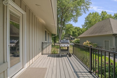 A peaceful deck area with a grill and greenery in the background, perfect for outdoor relaxation.