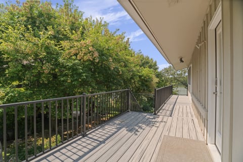Private balcony with lush green trees and colorful flowers, ideal for enjoying fresh air.