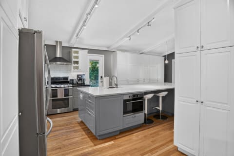 A modern kitchen with gray cabinetry, stainless steel appliances, and a spacious island with bar stools.