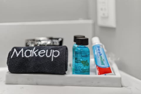 A marble tray displaying a dark towel labeled 'Makeup', two blue bottles of mouthwash, and a tube of toothpaste in a well-organized bathroom setting.