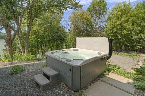 Private hot tub with a tranquil backdrop of trees and a peaceful waterfront.