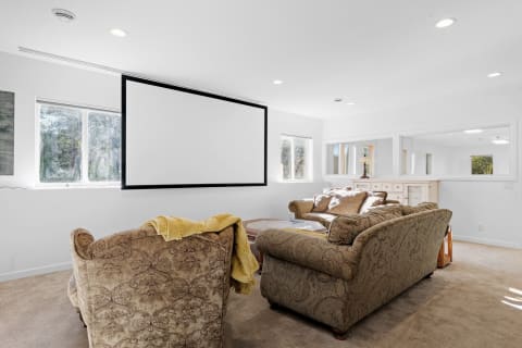 A modern lounge area with two sofas and a retractable projector screen.