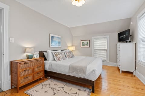 Cozy bedroom featuring a large bed, wooden dresser, and flat-screen TV.